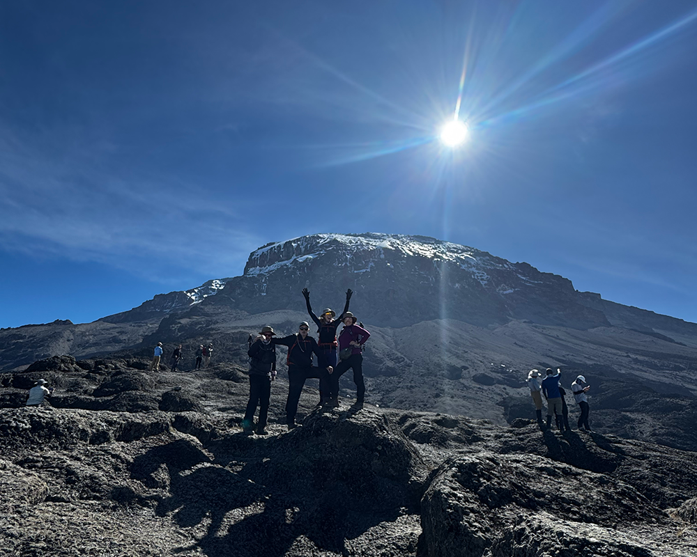 a team of people at the top of Kilimanjaro