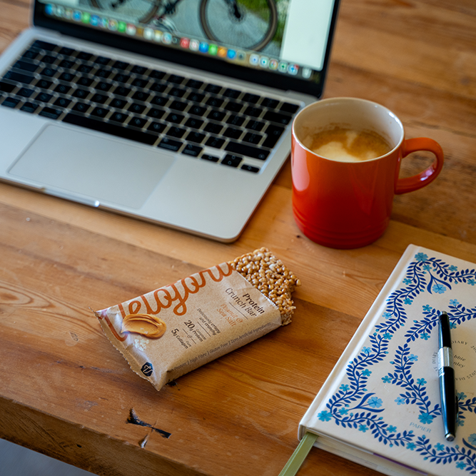 protein bar on a desk next to a laptop and cup of tea