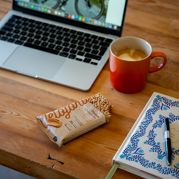 protein bar on a desk next to a laptop and cup of tea