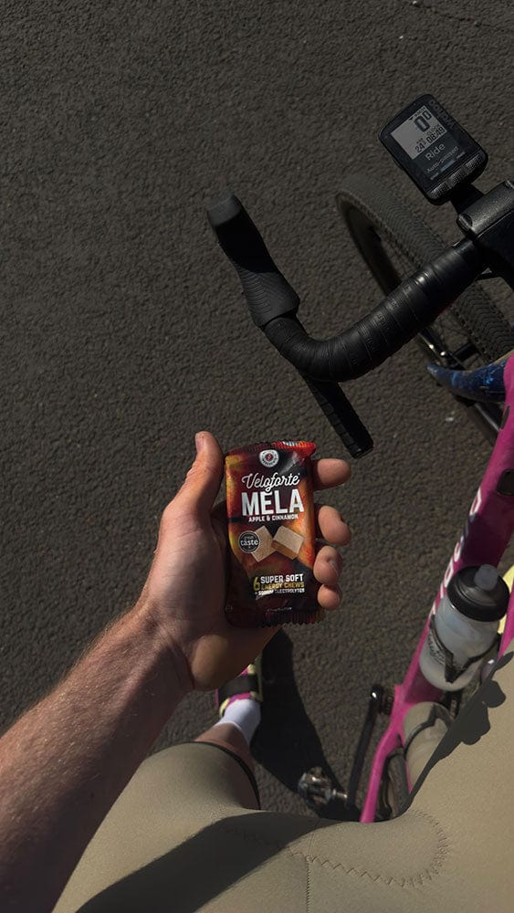 Hand holding a packet of Mela energy chews on a bicycle