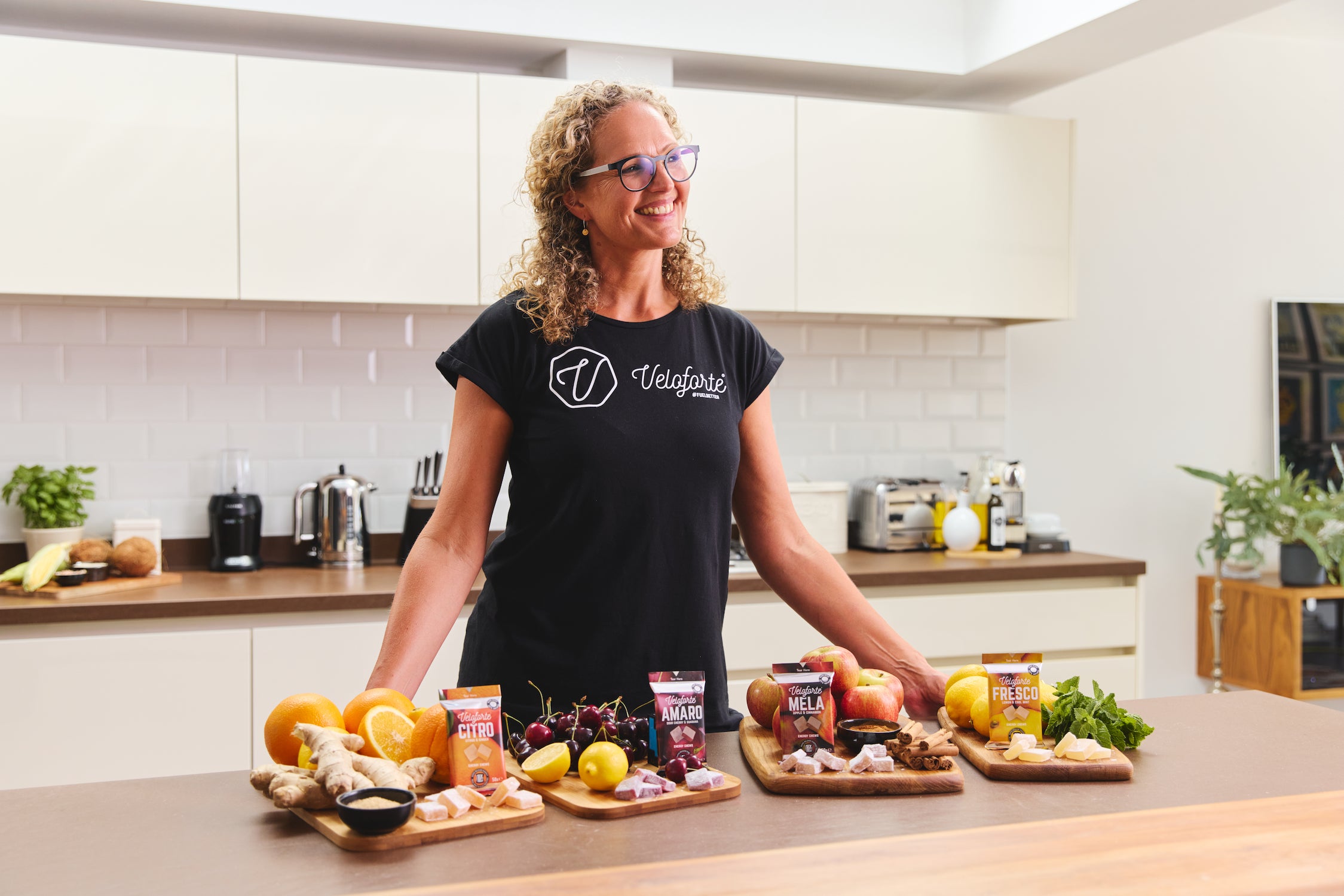 Veloforte founder Lara, standing in a kitchen with a selection of products