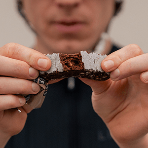 Man breaking Veloforte Protein Bar showing ingredients inside