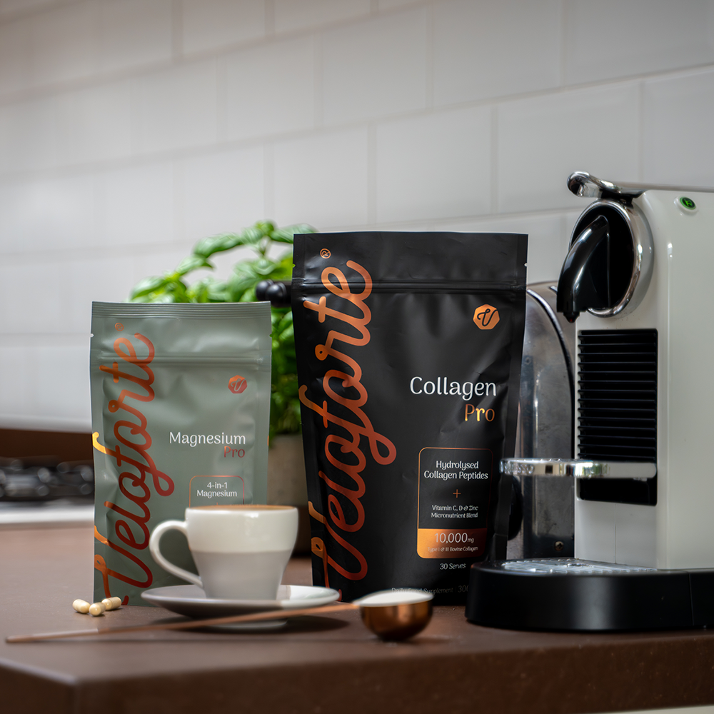 Velaforte collagen and magensium pouches on a kitchen counter with a coffee machine and cup.