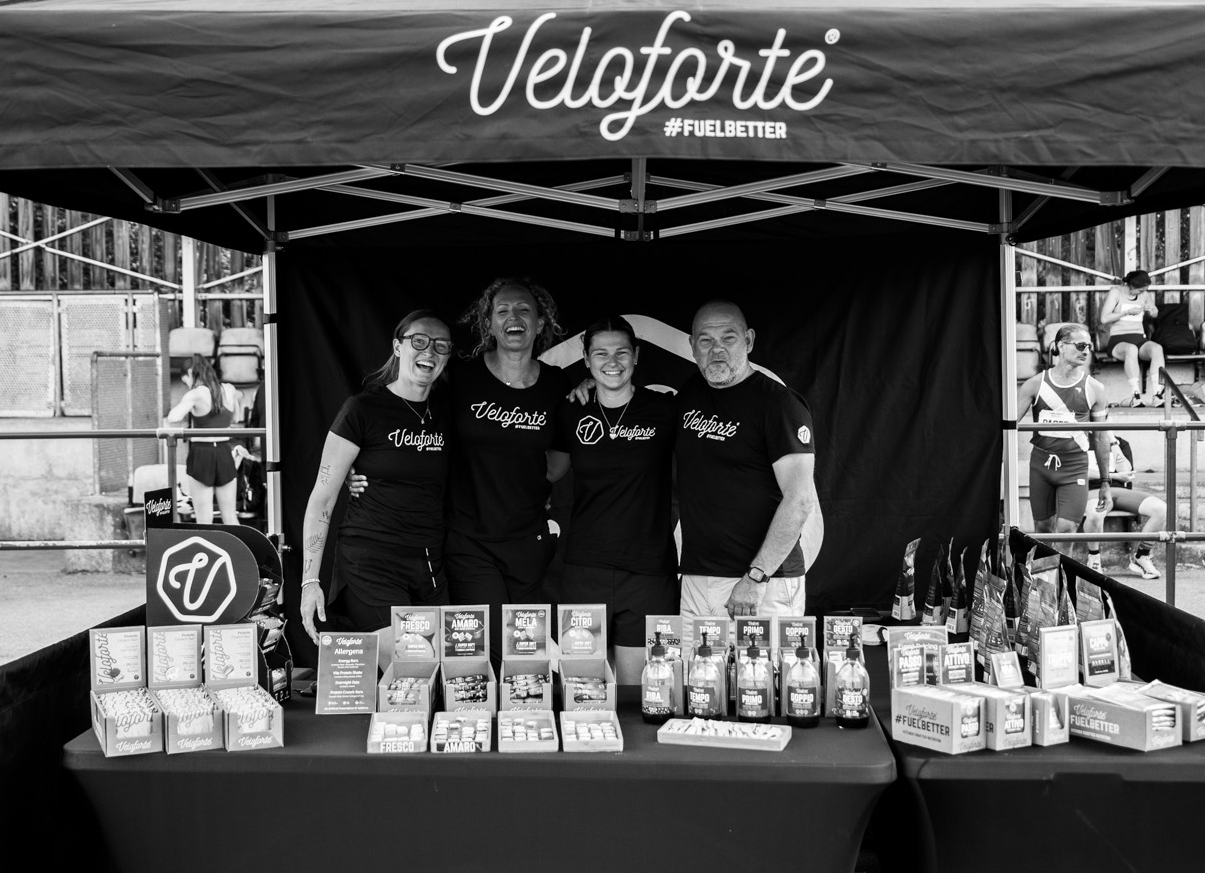 Group of people standing behind a table with Veloforte products under a Veloforte branded canopy.